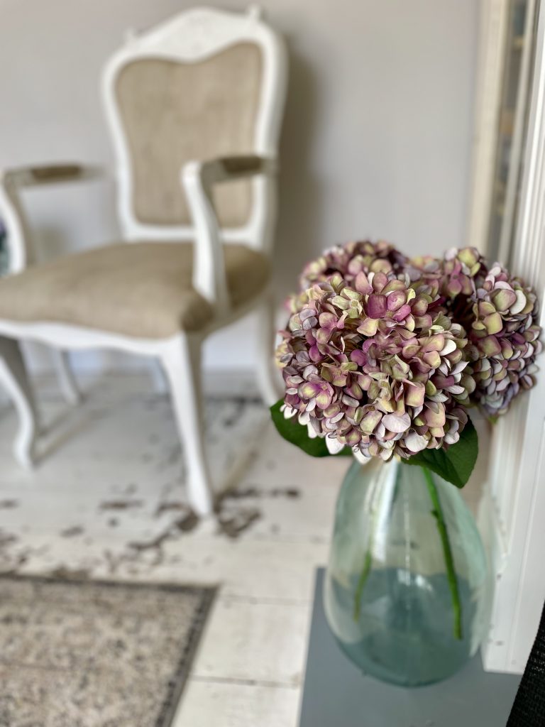 Picture of flowers in a vase with an old fashioned chair in the background in the sitting room at The House in Deal