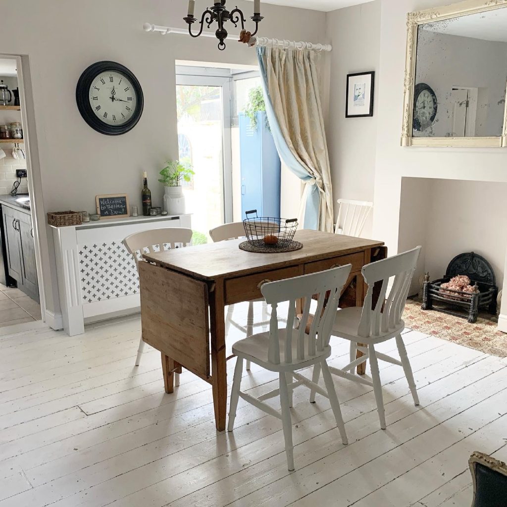 A wide shot of an old wooden dining table and 4 white chairs in the dining room of The House in Deal a holiday cottage in Deal kent