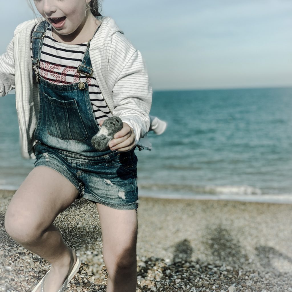 a picture of a little girl running on a beach while holding a heart shaped stone shot taken by the house in deal a holiday cottage to rent in Deal on the kent coast