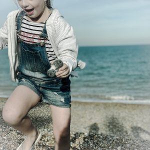 a picture of a little girl running on a beach while holding a heart shaped stone shot taken by the house in deal a holiday cottage to rent in Deal on the kent coast