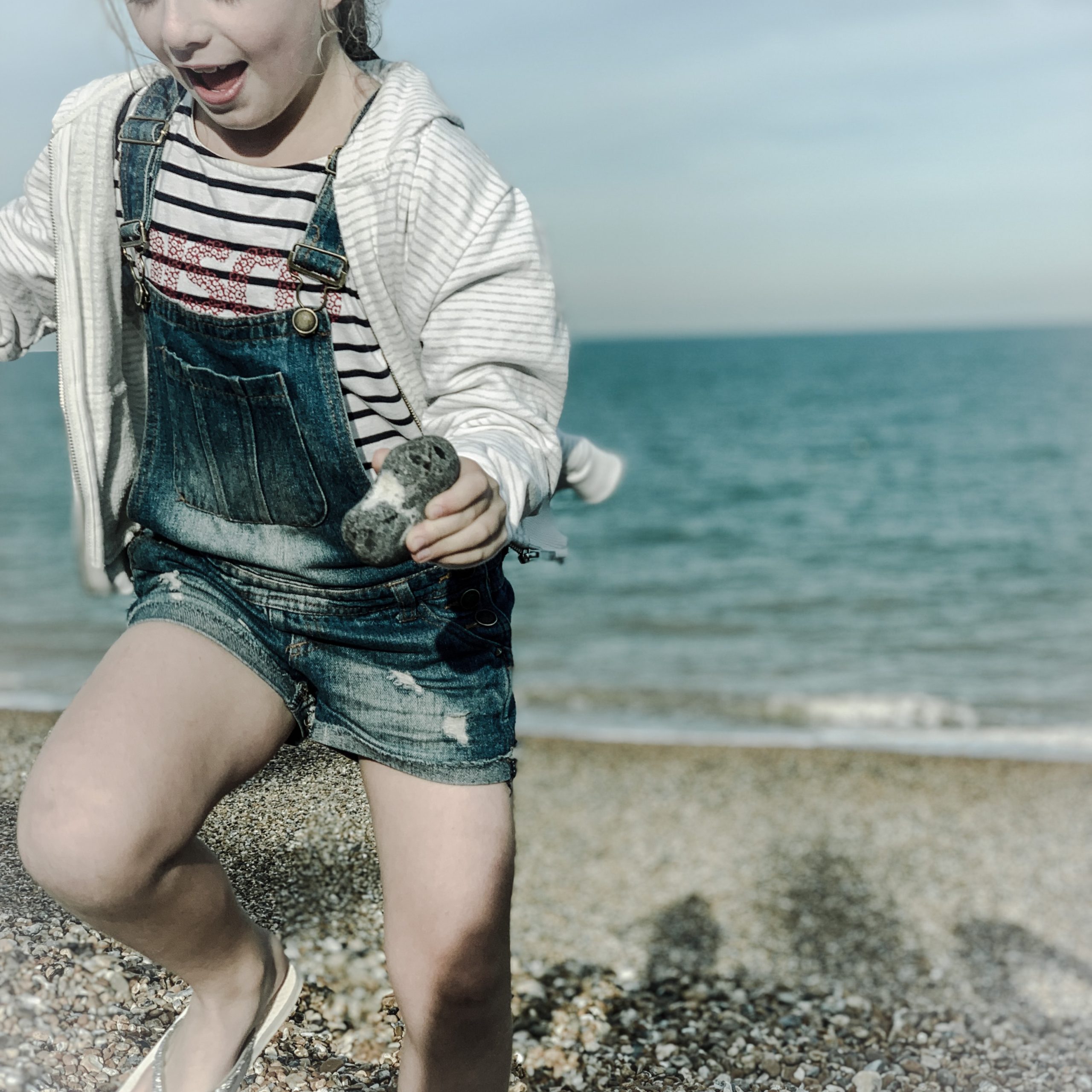 a picture of a little girl running on a beach while holding a heart shaped stone shot taken by the house in deal a holiday cottage to rent in Deal on the kent coast