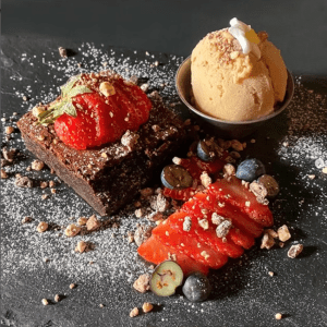 a delicious looking brownie covered in strawberries and scattered nuts